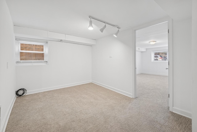 carpeted spare room with track lighting and baseboards