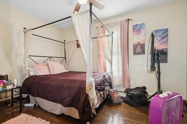 bedroom with a ceiling fan, wood finished floors, and a baseboard heating unit