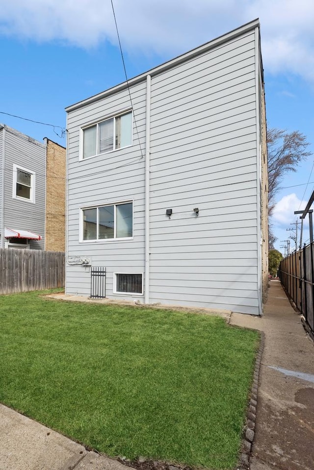 back of property with a lawn and fence