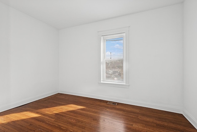 empty room with visible vents, baseboards, and dark wood-style floors