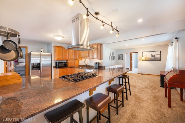 kitchen with light carpet, black appliances, a breakfast bar, a peninsula, and island range hood