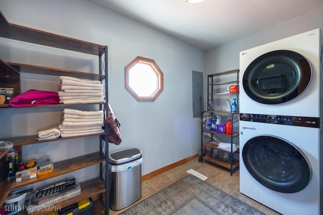 laundry area featuring laundry area, electric panel, baseboards, and stacked washing maching and dryer