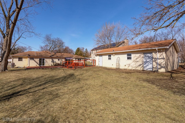 rear view of house with a yard, an outbuilding, a wooden deck, and a chimney