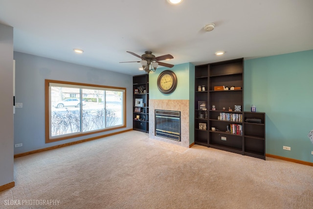 carpeted living room featuring built in shelves, ceiling fan, baseboards, recessed lighting, and a tile fireplace