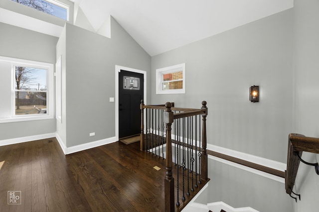 foyer featuring hardwood / wood-style flooring, baseboards, and vaulted ceiling