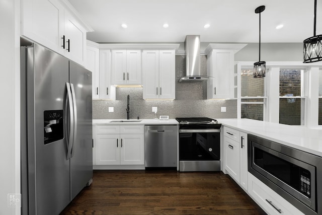 kitchen with appliances with stainless steel finishes, light countertops, a sink, and wall chimney exhaust hood