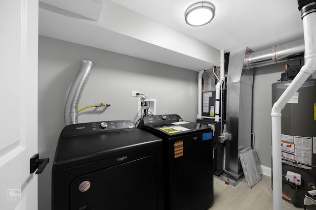 laundry room featuring water heater, laundry area, washing machine and dryer, and light wood-style floors