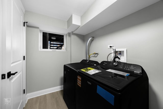 laundry room featuring laundry area, wood finished floors, washing machine and clothes dryer, and baseboards