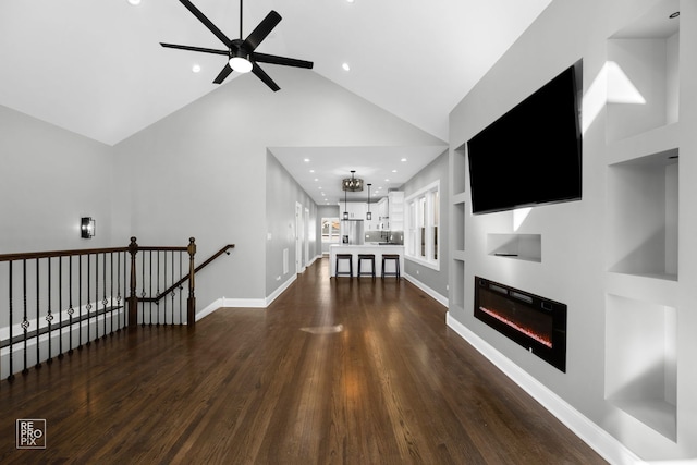 living area with high vaulted ceiling, recessed lighting, baseboards, dark wood-style floors, and a glass covered fireplace