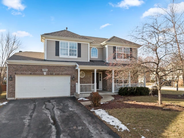 view of front of house featuring covered porch, a garage, brick siding, driveway, and a front lawn