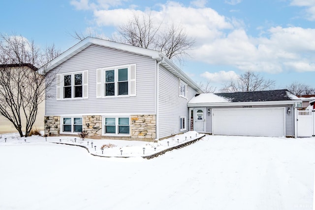 view of front facade featuring stone siding, fence, and an attached garage