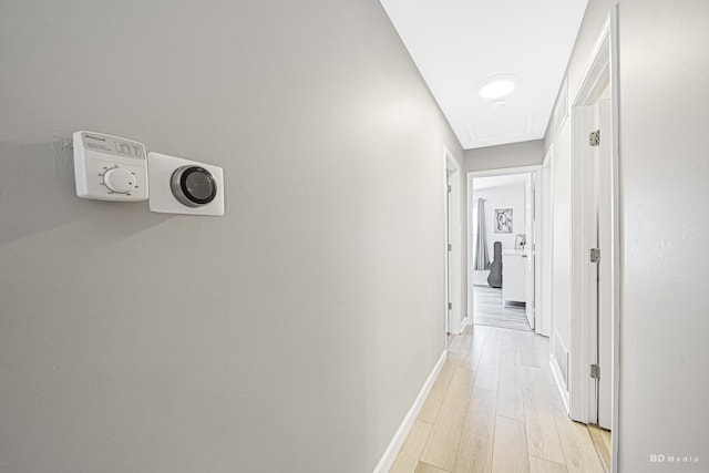 hall featuring light wood-type flooring and baseboards