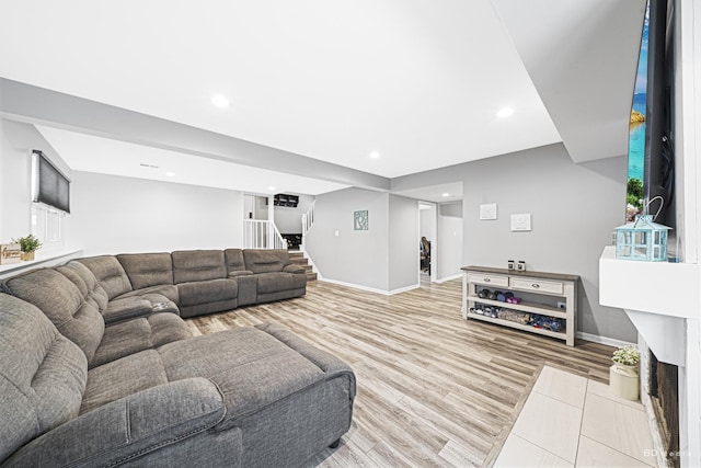 living room featuring light wood-style floors, recessed lighting, baseboards, and stairs