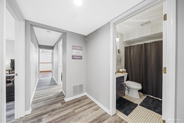 bathroom with toilet, vanity, wood finished floors, and visible vents