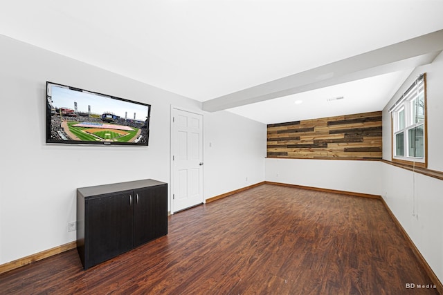 empty room with wooden walls, baseboards, and wood finished floors