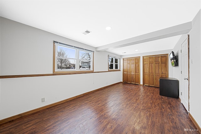 unfurnished bedroom with two closets, recessed lighting, visible vents, dark wood-type flooring, and baseboards