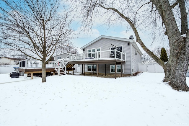 snow covered house featuring stairs, fence, and a wooden deck