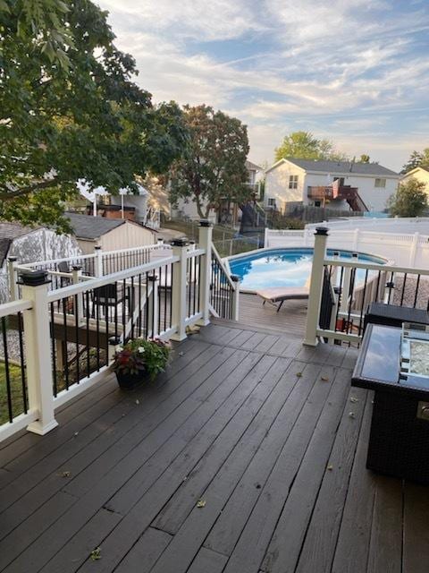 wooden terrace with a residential view, fence, and a fenced in pool