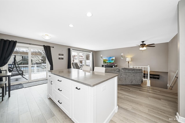 kitchen with light wood finished floors, plenty of natural light, white cabinetry, and a center island