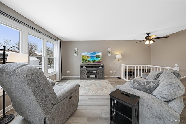 living room with a ceiling fan, baseboards, and light wood finished floors