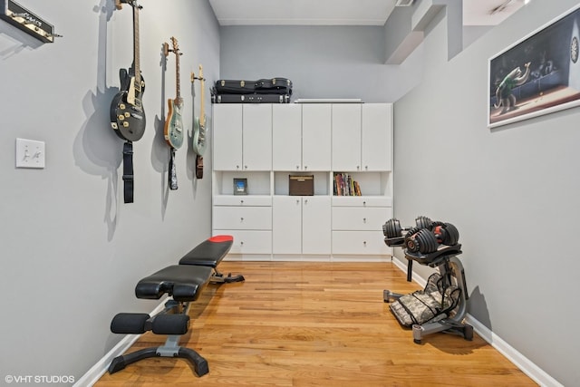 workout room with baseboards and light wood-type flooring