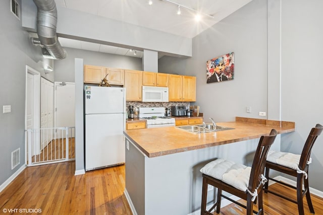 kitchen featuring visible vents, light brown cabinetry, decorative backsplash, a peninsula, and white appliances