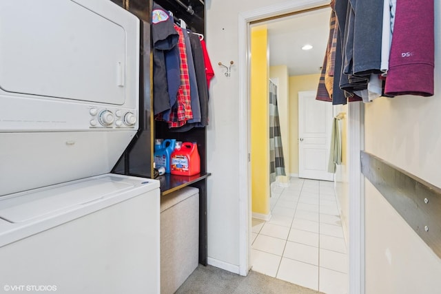 laundry room featuring laundry area, stacked washer / dryer, baseboards, and tile patterned floors