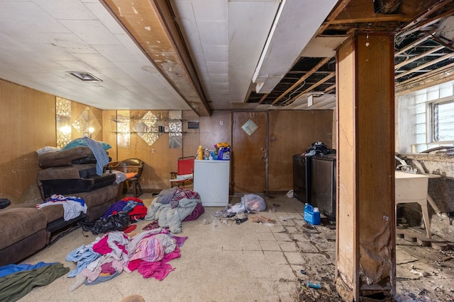 basement featuring washer / dryer, wooden walls, and refrigerator