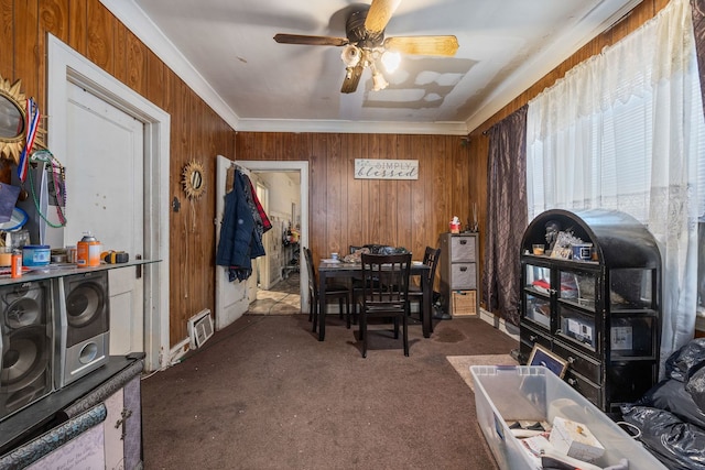 office space featuring ceiling fan, carpet floors, wood walls, visible vents, and ornamental molding