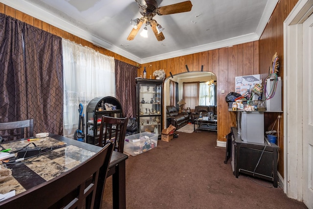 interior space featuring ornamental molding, arched walkways, wooden walls, and a ceiling fan