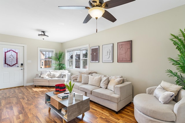 living room featuring ceiling fan, baseboards, and wood finished floors