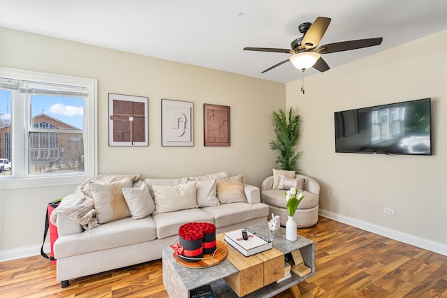 living area featuring wood finished floors, baseboards, and ceiling fan