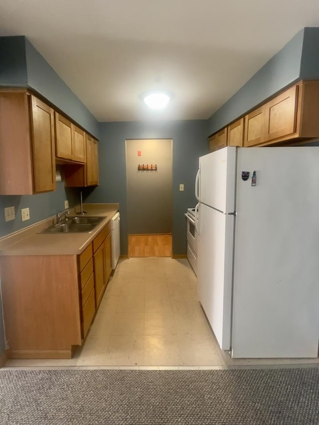 kitchen featuring white appliances, light countertops, and a sink