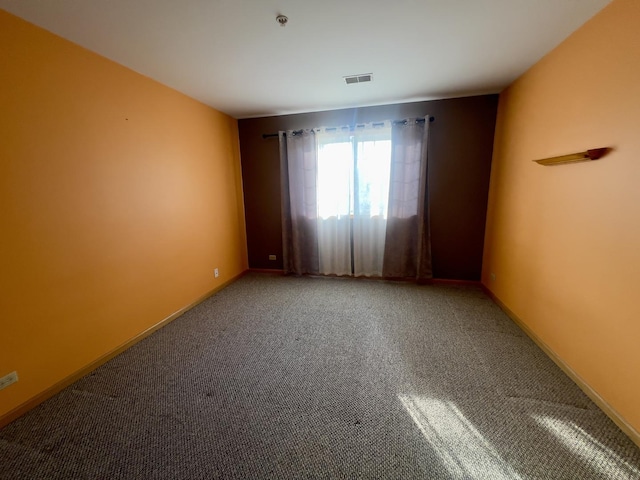 carpeted empty room featuring baseboards and visible vents