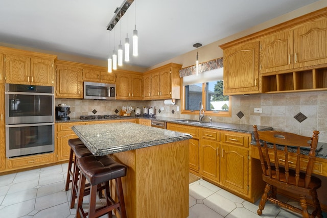 kitchen featuring tasteful backsplash, a center island, light tile patterned floors, stainless steel appliances, and a sink