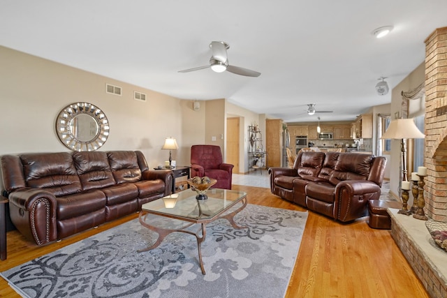 living room featuring a ceiling fan, light wood-style floors, and visible vents