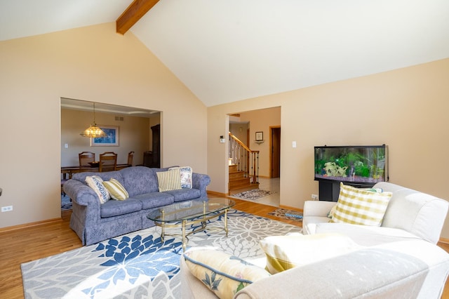 living area with baseboards, stairs, beam ceiling, wood finished floors, and high vaulted ceiling