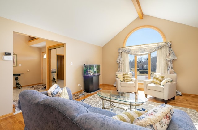 living area featuring beamed ceiling, high vaulted ceiling, baseboards, and wood finished floors