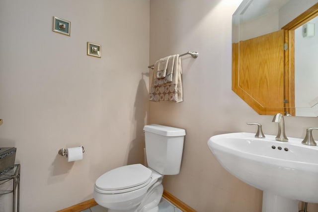 bathroom featuring toilet, baseboards, and a sink