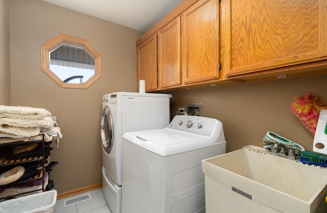 washroom featuring baseboards, visible vents, cabinet space, a sink, and washing machine and dryer