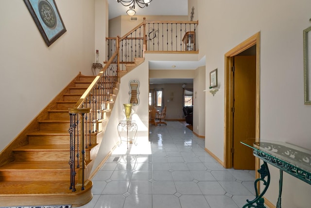 entryway with visible vents, baseboards, stairs, and a towering ceiling