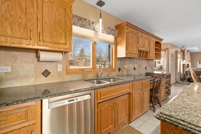 kitchen with light tile patterned floors, dark stone countertops, dishwasher, and a sink