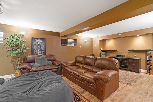 living area with beam ceiling, baseboards, and light wood-type flooring