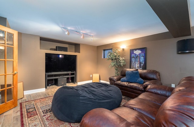 living area with track lighting, wood finished floors, and baseboards