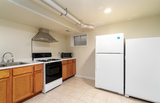 kitchen featuring gas stove, freestanding refrigerator, a sink, stainless steel microwave, and wall chimney range hood