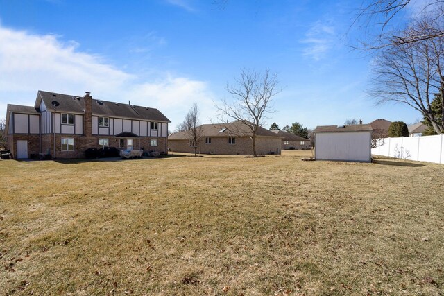 view of yard featuring an outdoor structure, a shed, and fence