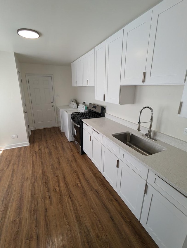 kitchen with light countertops, washer and clothes dryer, a sink, and white cabinets