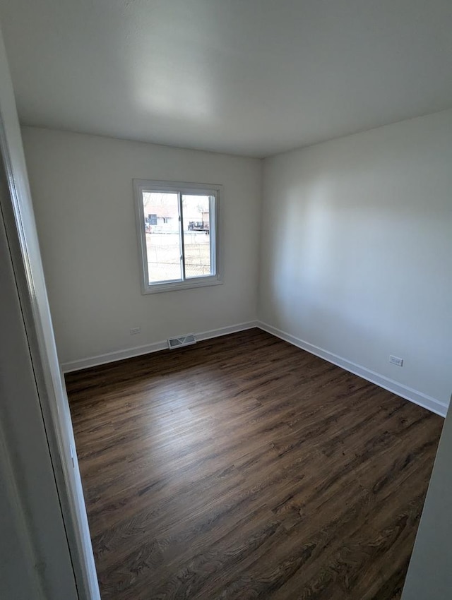 spare room featuring dark wood-style floors, baseboards, and visible vents