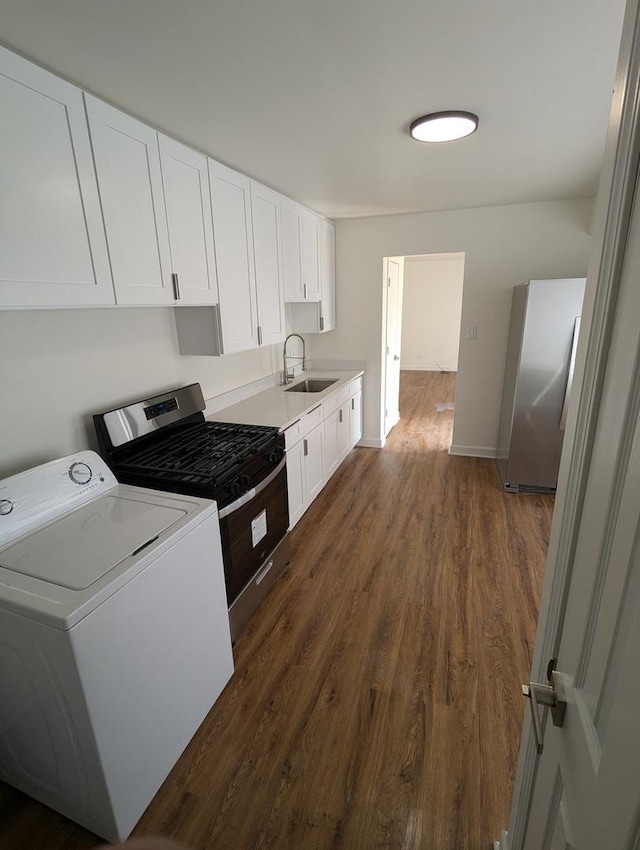 kitchen featuring white cabinets, washer / dryer, stainless steel appliances, and a sink