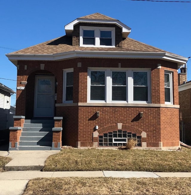 bungalow-style house with a shingled roof and brick siding